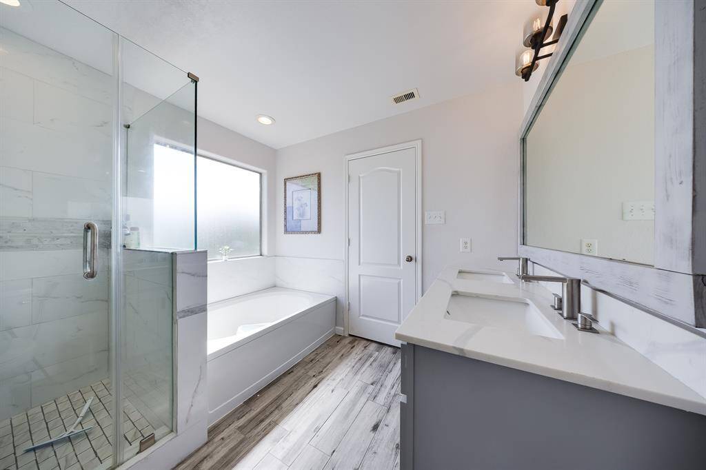 Primary bathroom full of warm light coming in from large windows.