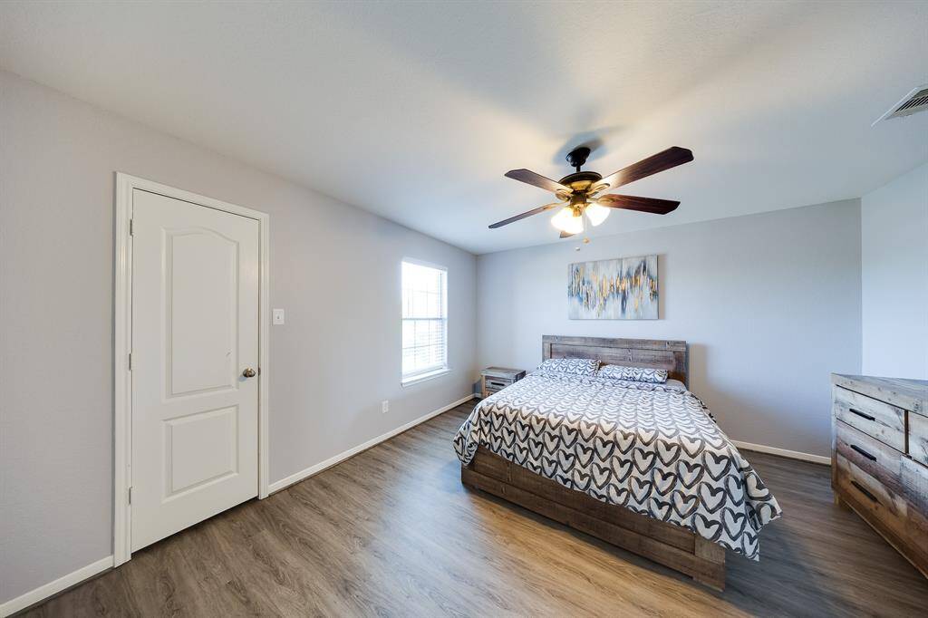 Natural light fills the cozy bedroom with wood-look floors and minimalist decor.