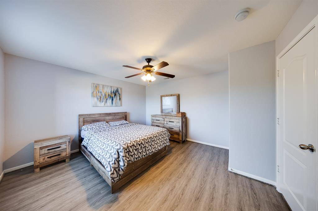 Rustic-style bedroom with ceiling fan, neutral walls, and updated flooring.