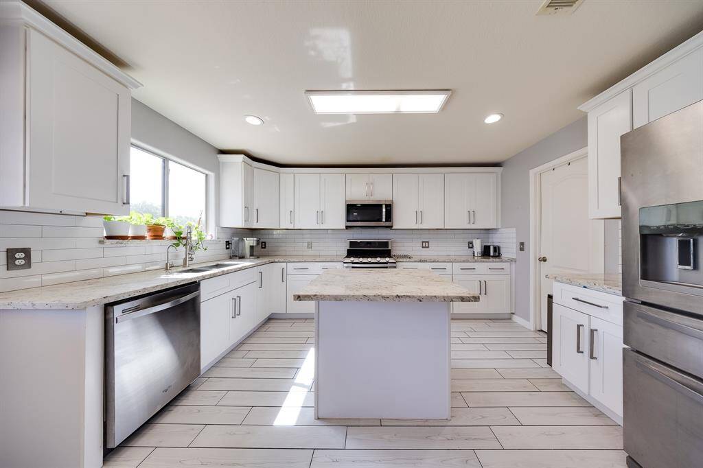 Chef’s kitchen with island, subway tile backsplash, and deep drawer storage.