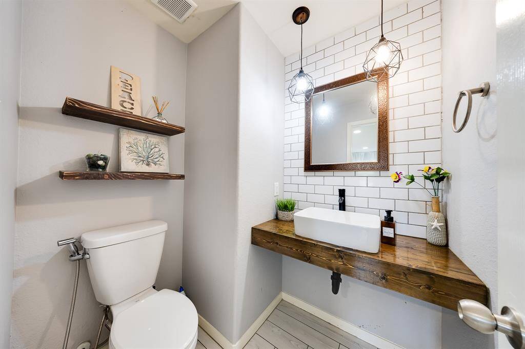 Chic powder room with vessel sink, wooden vanity, and statement pendant lighting.