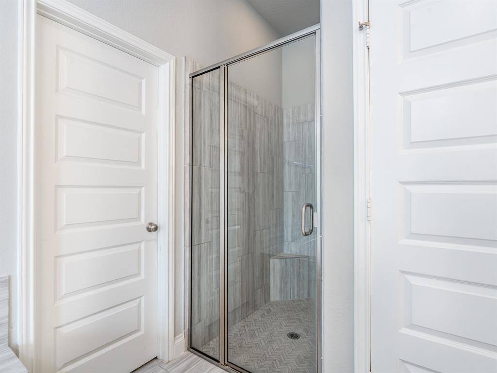 Separate shower has a herringbone pattern tile floor with a ledge, both are upgrades.