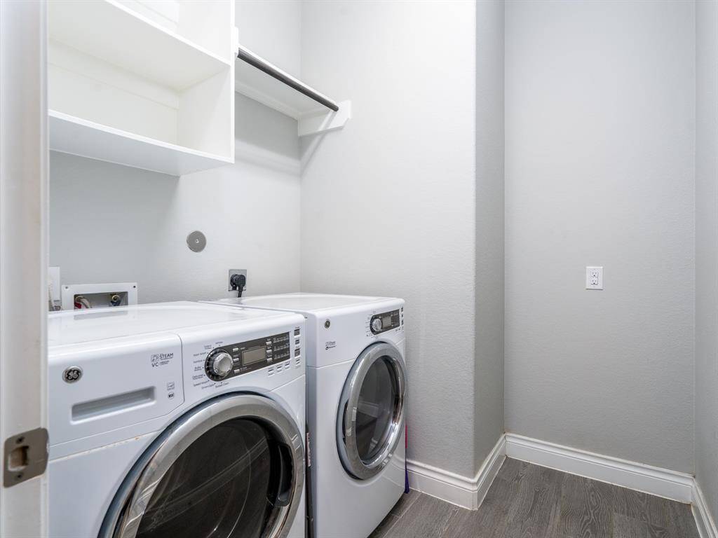 Laundry room with hanging rack and room for an additional fridge.