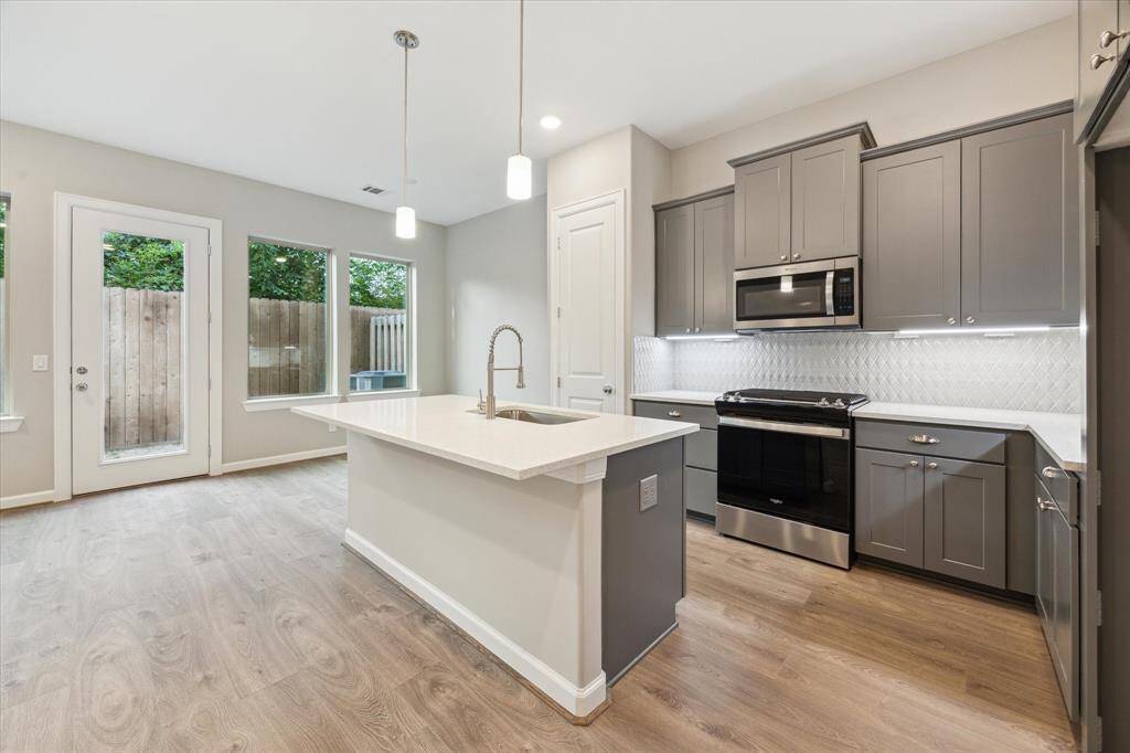 A chef’s kitchen with quartz countertops, soft-close cabinetry, stainless steel appliances, and luxe tile backsplash.