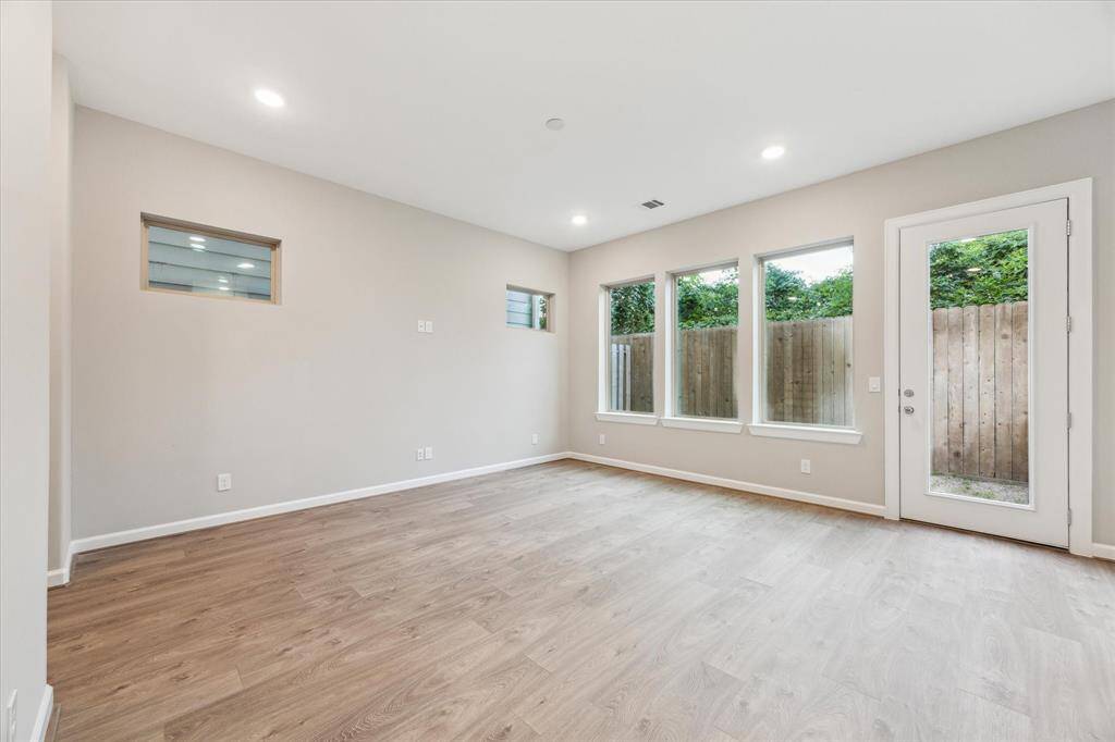 Open-concept living and dining area with expansive windows, wide plank flooring, and recessed lighting.