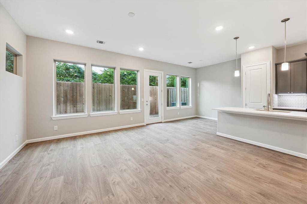 Bright and open living space with wide-plank floors, large windows, and access to the private backyard.