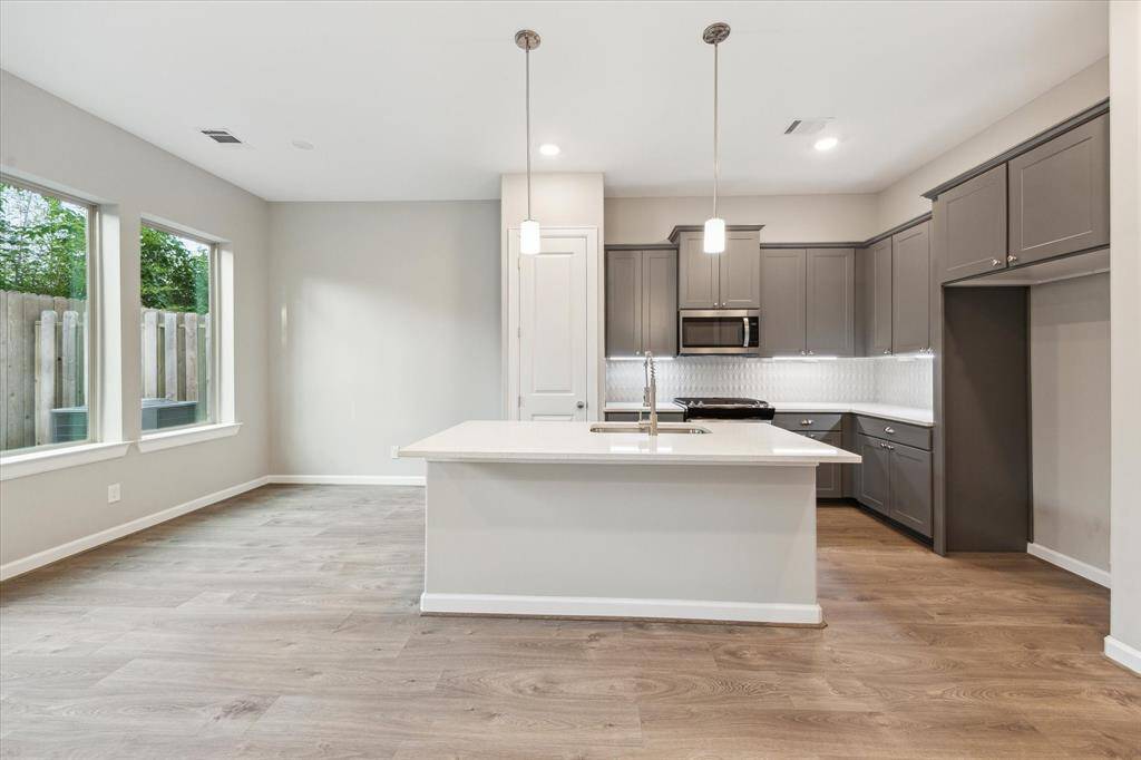 Features sleek quartz countertops, cabinetry, and a stylish tile backsplash. Stainless steel appliances and a large island make it ideal for cooking and entertaining.