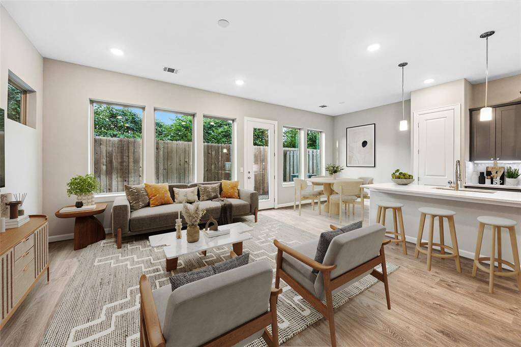 Natural light floods the living space through oversized windows, creating a seamless indoor-outdoor connection.