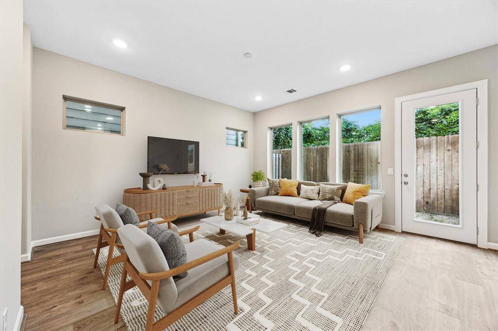 Bright and open living space with wide-plank floors, large windows, and access to the private backyard.