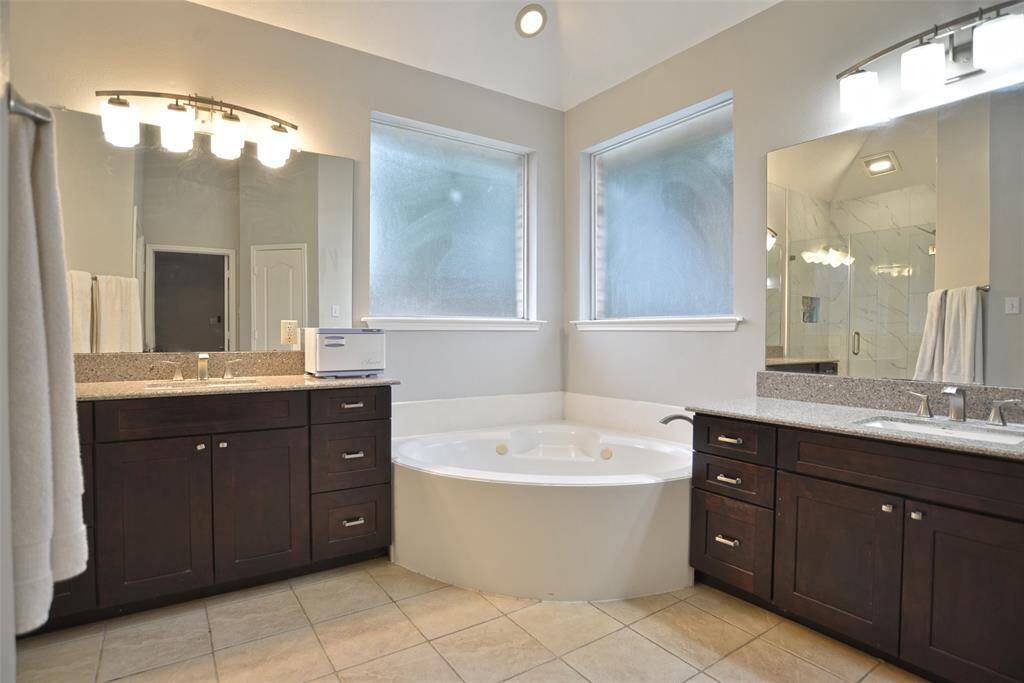 Primary Bath features dual vanities and corner tub