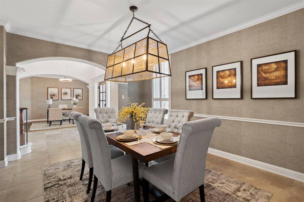 Light and bright formal diningroom features large windows,high ceiling, crown molding, chair rail, custom paint, chandelier, andtile flooring.