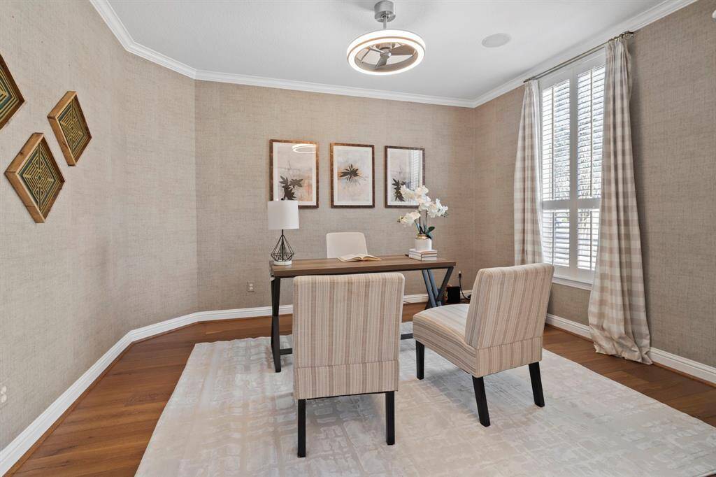 The den features beautiful floors, large windows with shutters, custom grass wallpaper, and crown molding.