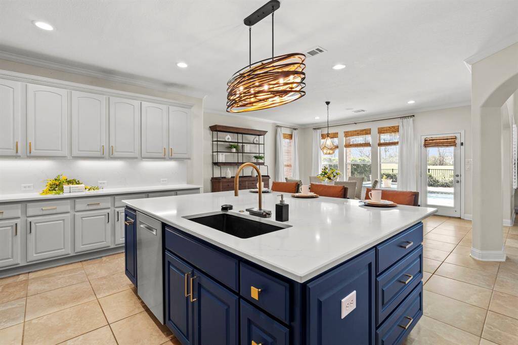 The newly remodeled kitchen has an island, tileflooring, brushed gold hardware, and stainless steelappliances.