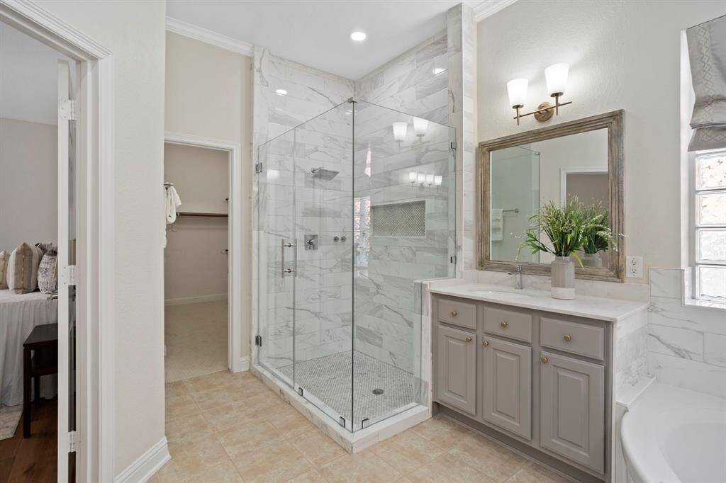 The primary bathroom also has a walk-in shower with glass door and tile surround.
