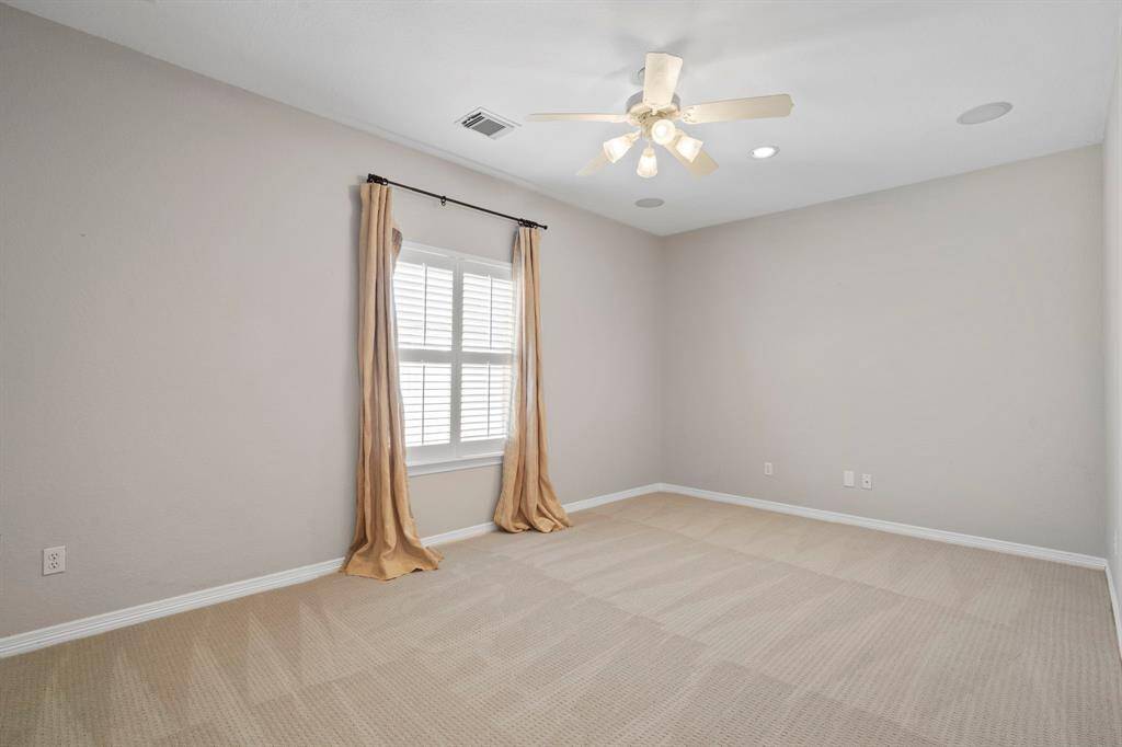 Secondary bedroom features awindow, ceiling fan, and plush carpet.