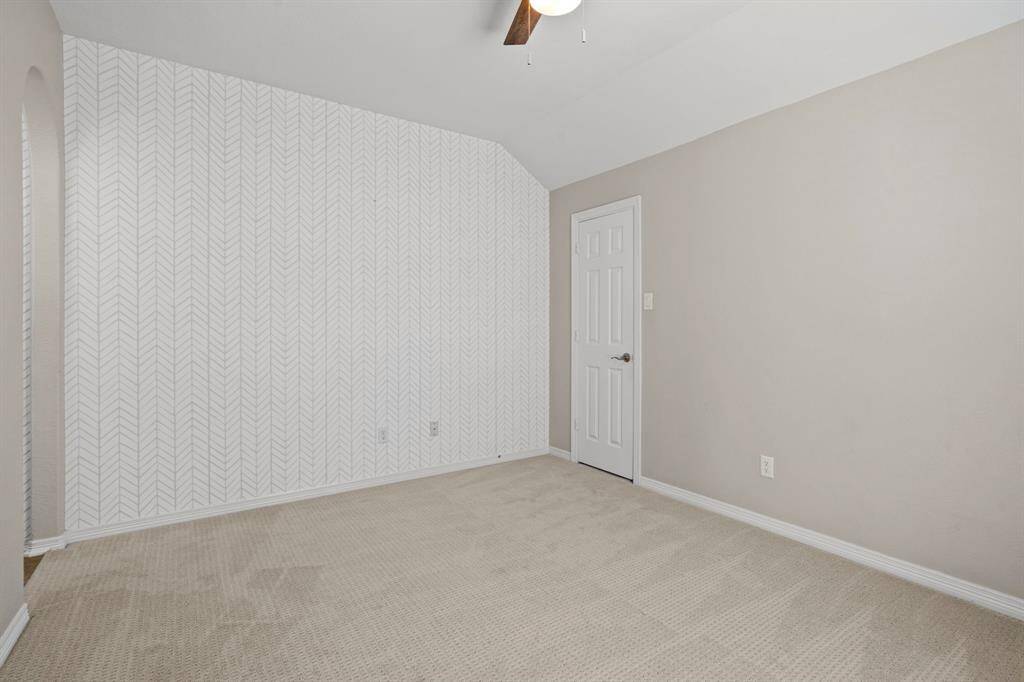 Fifth bedroom features a ceiling fan, accent wall, and plush carpet.