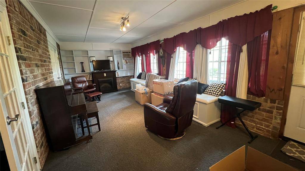 Sunroom with a great seating area including benches, built in shelving, mock electric fireplace and window unit.