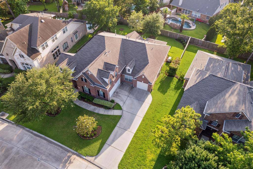 A charming two-story brick home with a well-maintained lawn and a spacious driveway. The backyard features ample green space, ideal for outdoor activities.