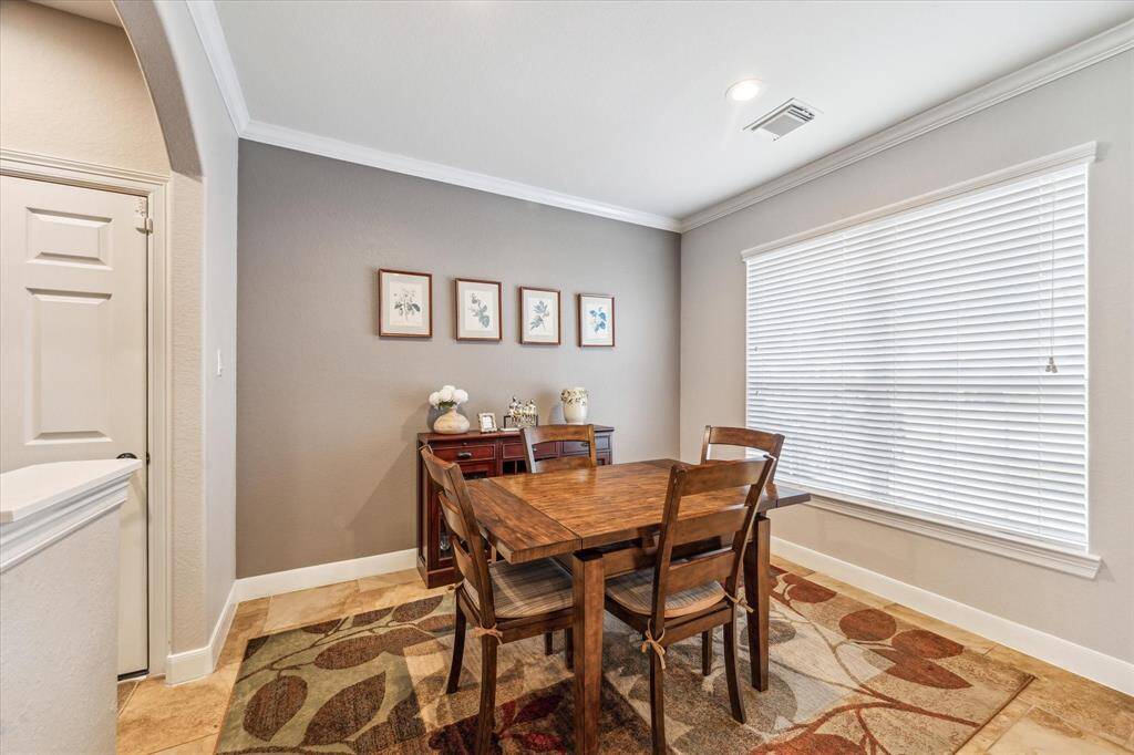 This dining area features a neutral walls  and ample natural light from a large window with blinds.