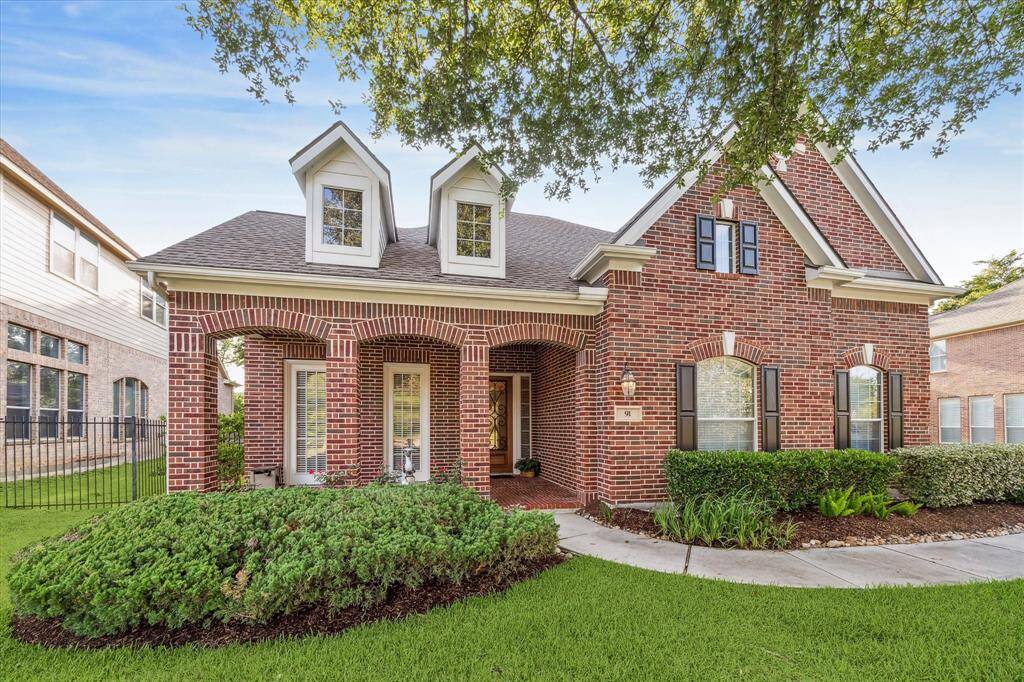 Charming home with a classic design, featuring three dormer windows and a covered front porch. The well-maintained landscaping includes lush green grass and neatly trimmed shrubs, offering great curb appeal.