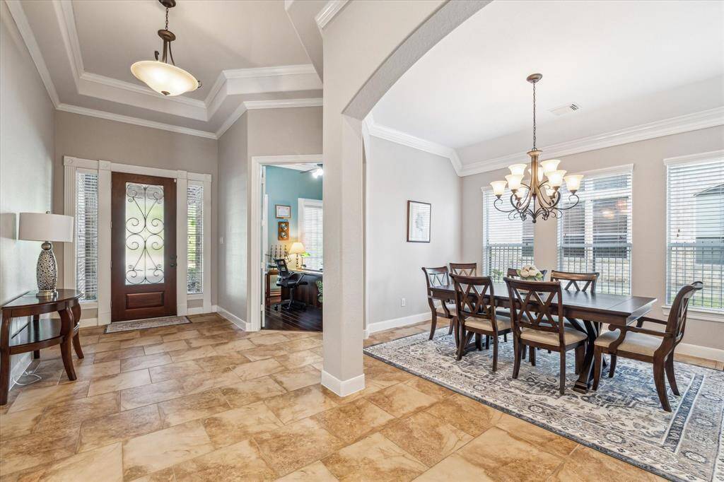 Elegant tile flooring, leading to a formal dining room. The dining area features a stylish chandelier and large windows for ample natural light. The room exudes a warm and inviting atmosphere, perfect for entertaining.