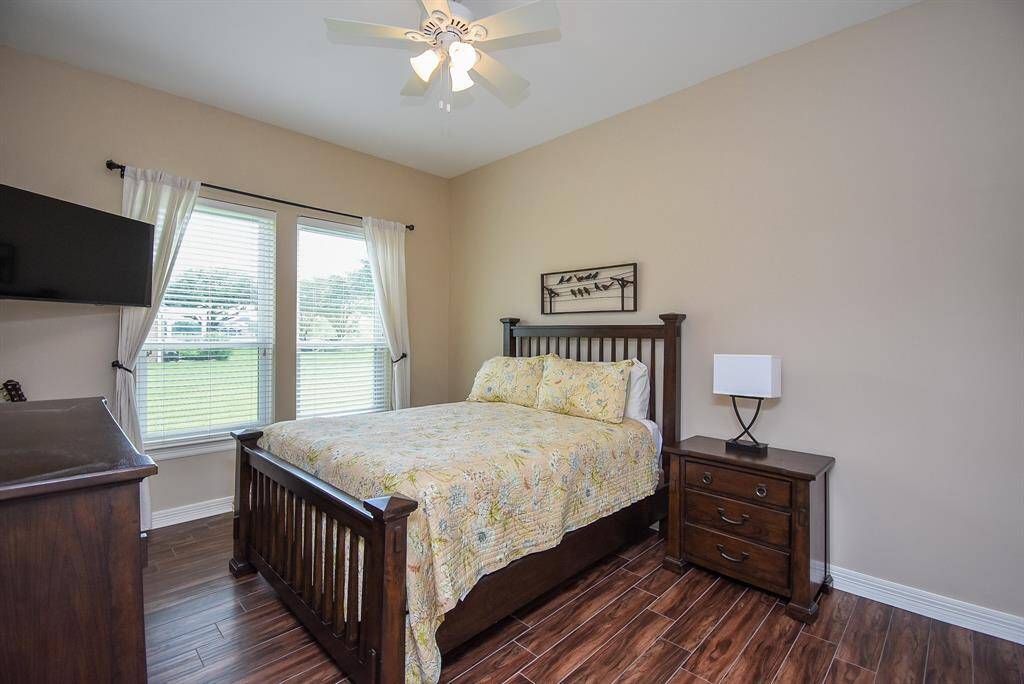 Bedroom 2 with wood tile flooring, updated lighting and ceiling fan.