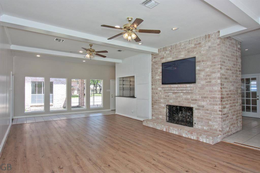 Living room towards front view of courtyard, wet bar and warmth of brick fireplace.