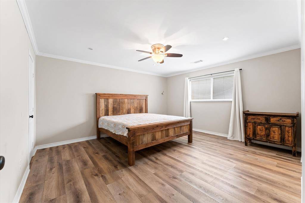 Primary bedroom with luxury vinyl flooring complemented by neutral walls.