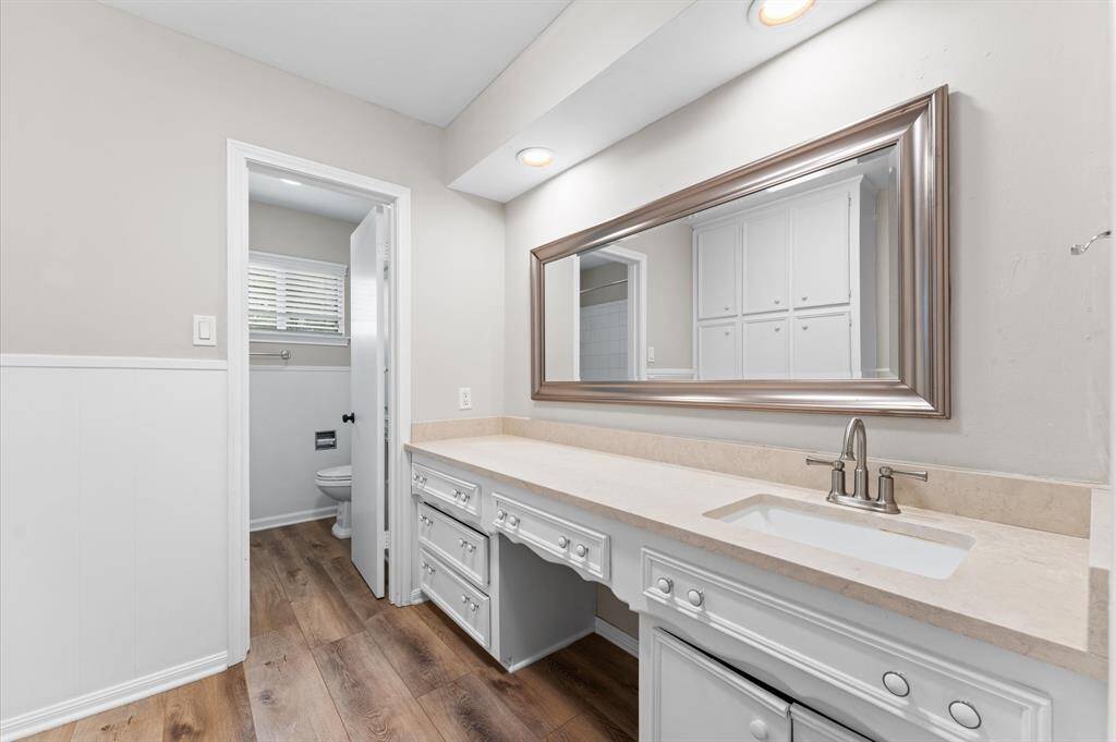 Upstairs secondary bathroom features a wide vanity with ample counter space, a large framed mirror.