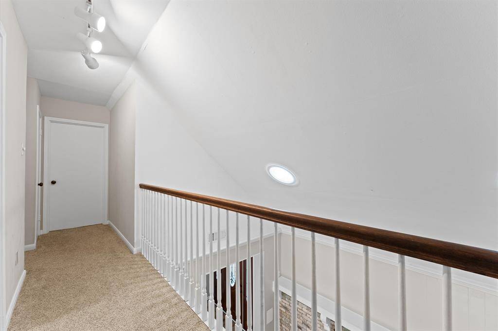 Carpeted hallway with recessed lighting and a skylight provide illumination.