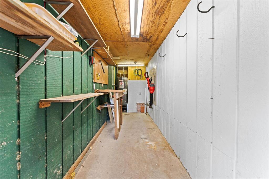 Storage room with wooden shelves, hooks for hanging items, and a workbench. Perfect to store your lawnmower!