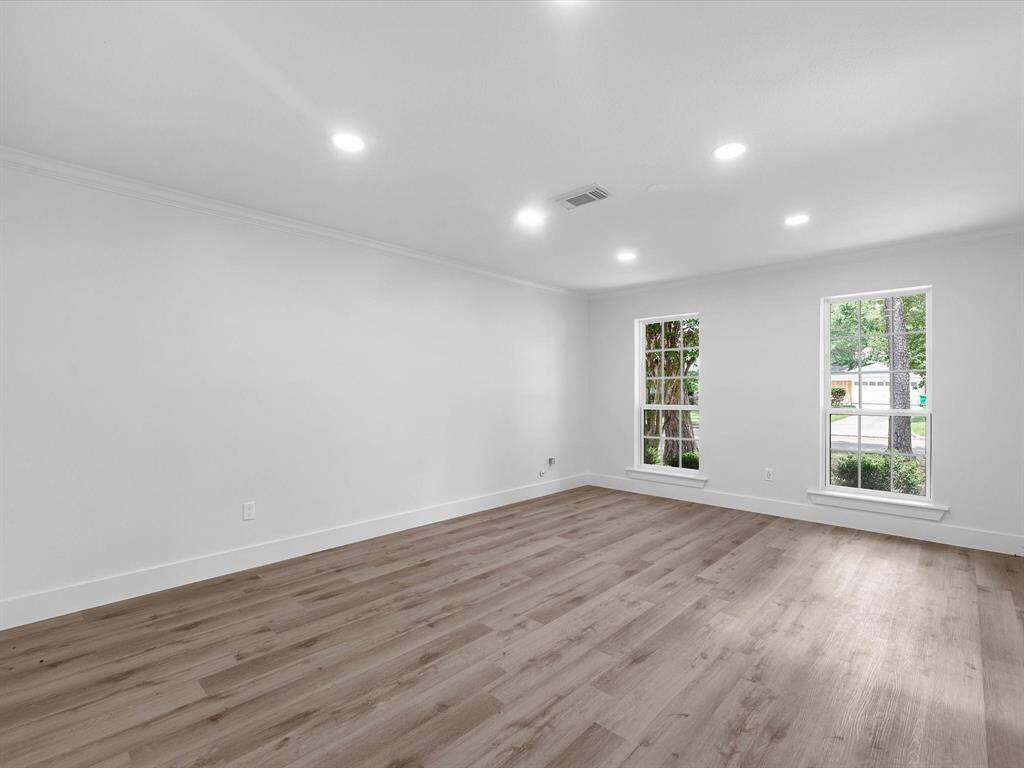 This room features spacious, open living with light wood floors, fresh white walls, and large windows providing ample natural light. Ideal for creating a bright and welcoming space.