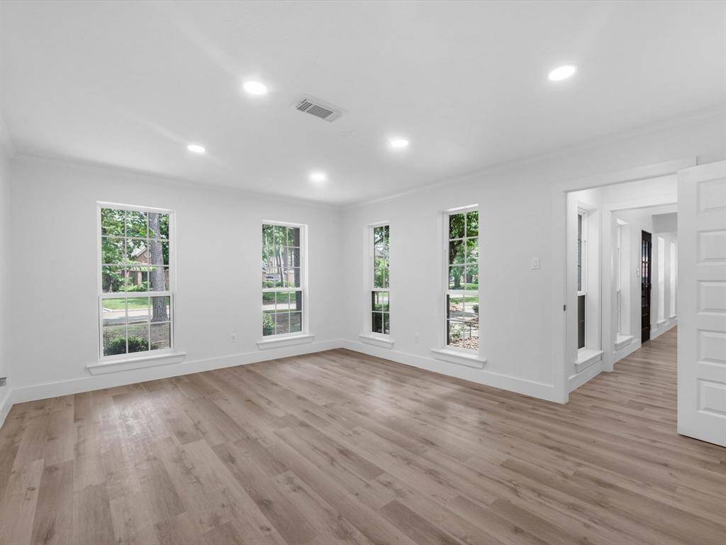 This photo shows a bright, spacious living area with large windows, light wood flooring, and recessed lighting, offering a modern and inviting atmosphere.