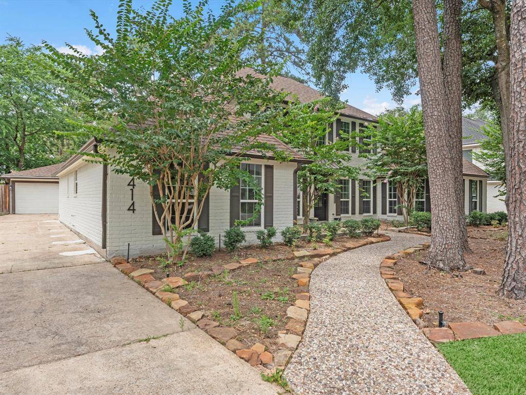 This charming home features a welcoming stone pathway leading to a two-story entrance, surrounded by mature trees and neatly landscaped garden beds. The exterior combines a clean, modern look with classic elements, offering an inviting curb appeal.