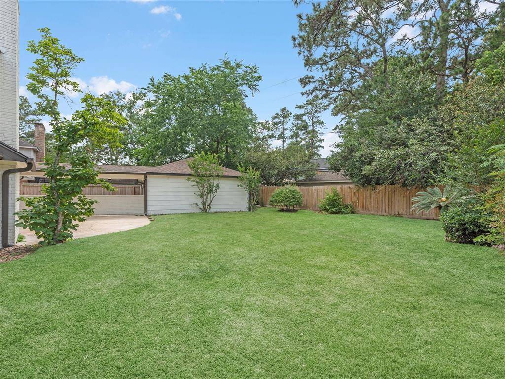 Spacious backyard with lush grass, mature trees, and a wooden fence for privacy. Ideal for outdoor activities and relaxation.