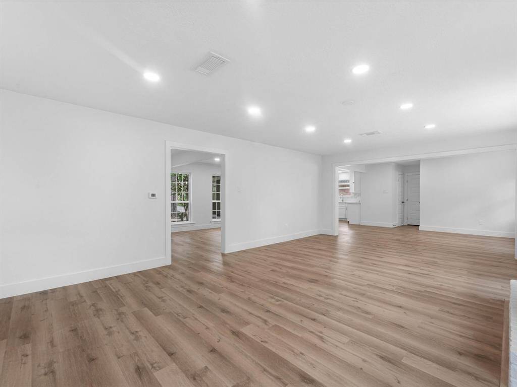 Spacious open-concept living area with sleek hardwood floors and recessed lighting, featuring a seamless flow into adjacent rooms and plenty of natural light.