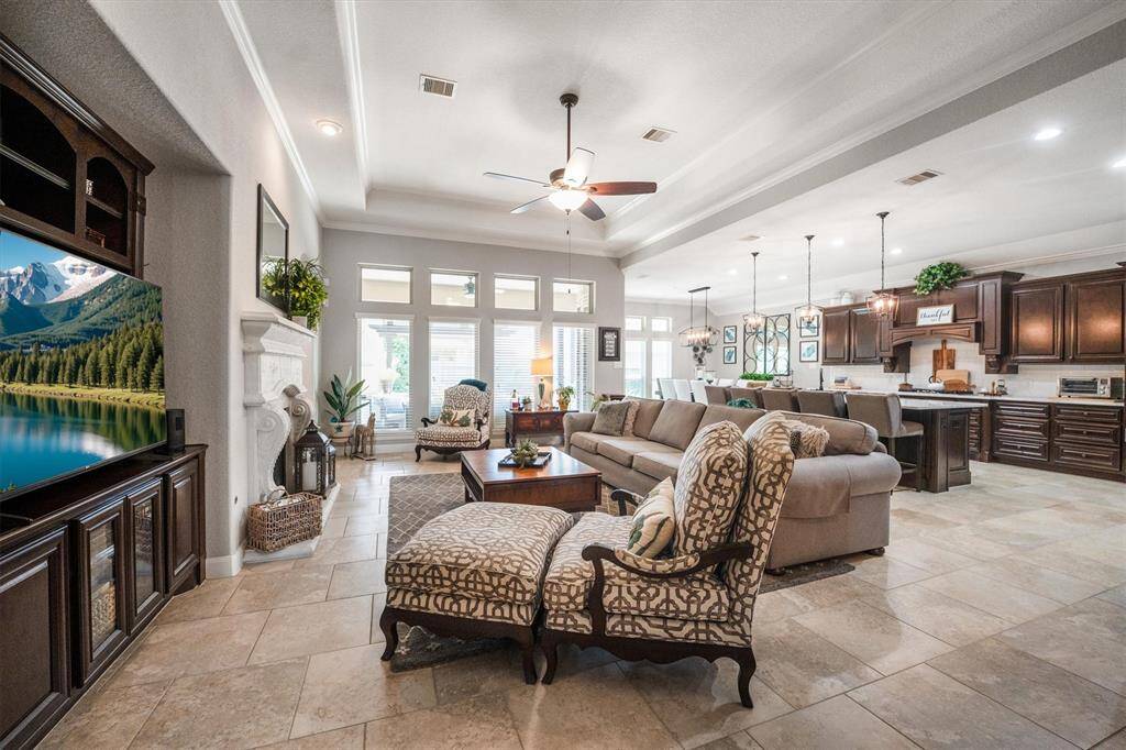 Spacious family room with a built-in entertainment center, stone-surround gas fireplace, elegant tile flooring, and a tray ceiling with crown molding. Enjoy abundant natural light from the wall of windows.