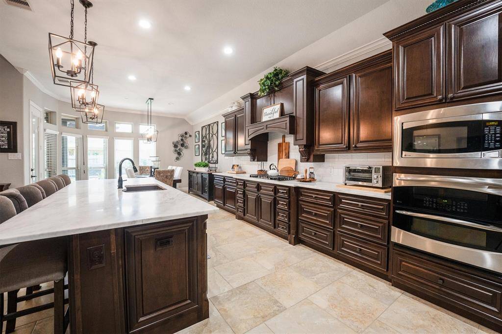 This kitchen boasts sleek stainless steel appliances, double ovens, and a refrigerator that stays. Enjoy the elegance of upgraded backsplash, chandelier, and pendant lighting.