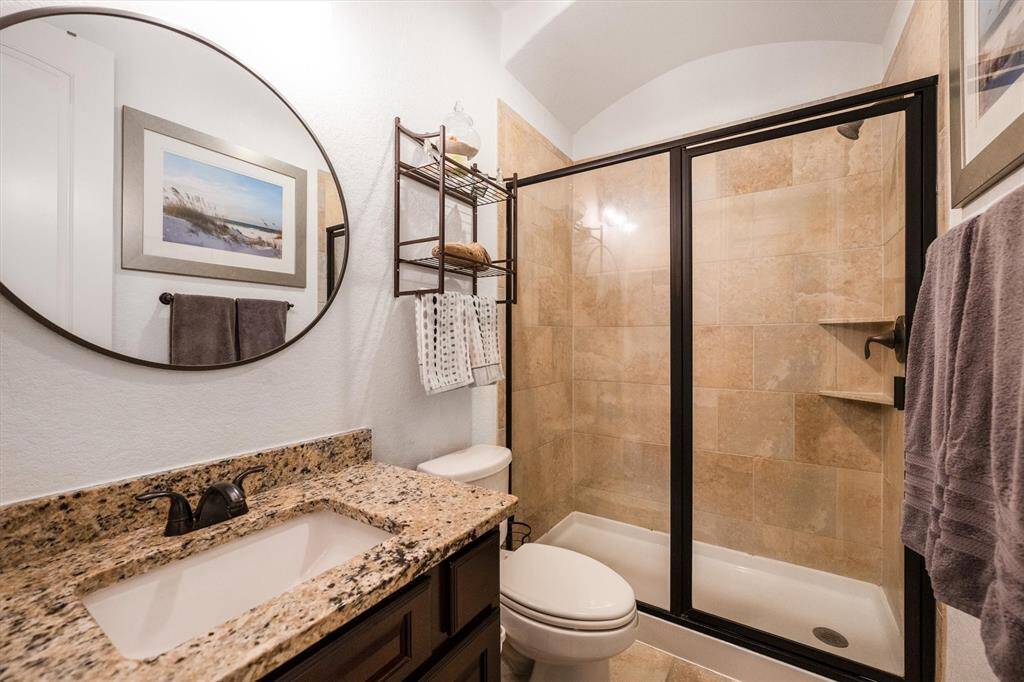 Elegant first full bathroom featuring a walk-in shower and luxurious granite countertops.