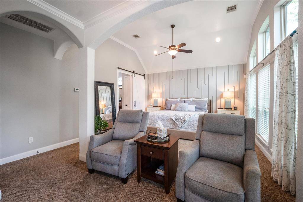 Elegant primary suite featuring a cozy sitting area with space on the wall for a TV for ultimate relaxation.