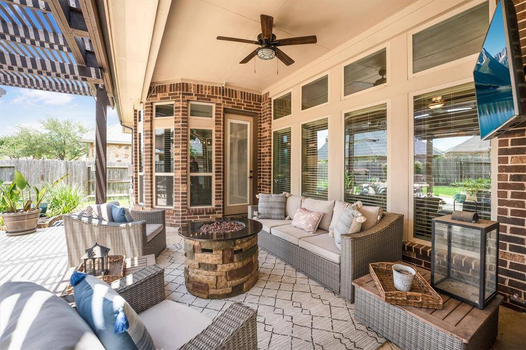 Experience the perfect backyard retreat with a ceiling fan, outdoor TV, and elegant flagstone flooring—ideal for relaxation and entertainment.
