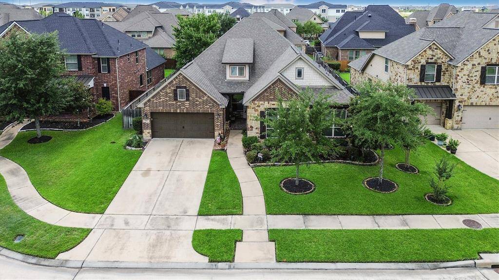Aerial view showcasing the spacious double-wide driveway and a convenient 3-car tandem garage.