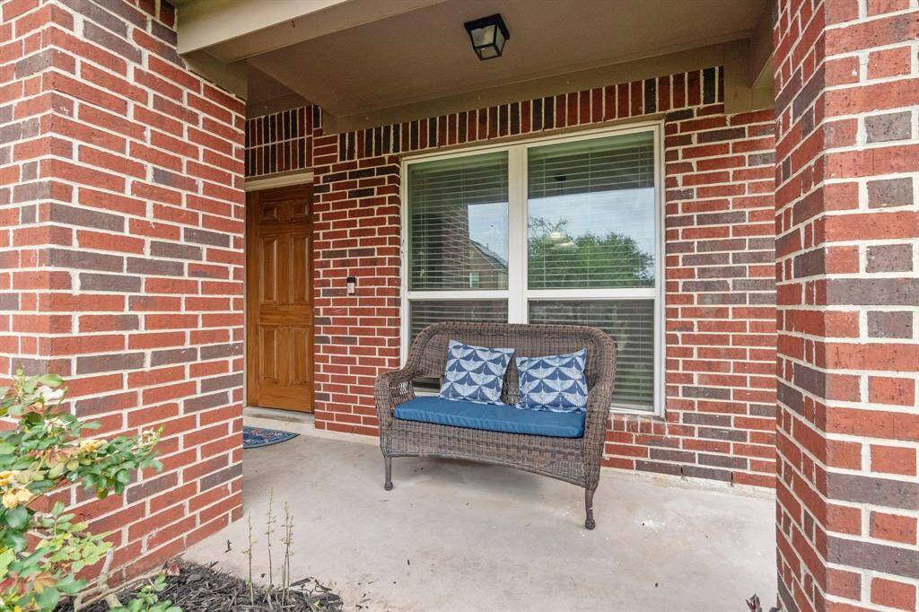 This inviting front porch features classic red brick, a cozy space for a bench or rocker, and a front door, offering a charming entryway to your home.