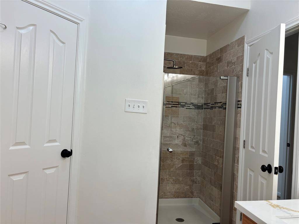 Primary bath features updated walk-in shower, with new tile and faucets.