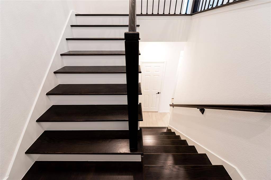 modern staircase with dark wood steps and sleek railings, leading up to a bright hallway.