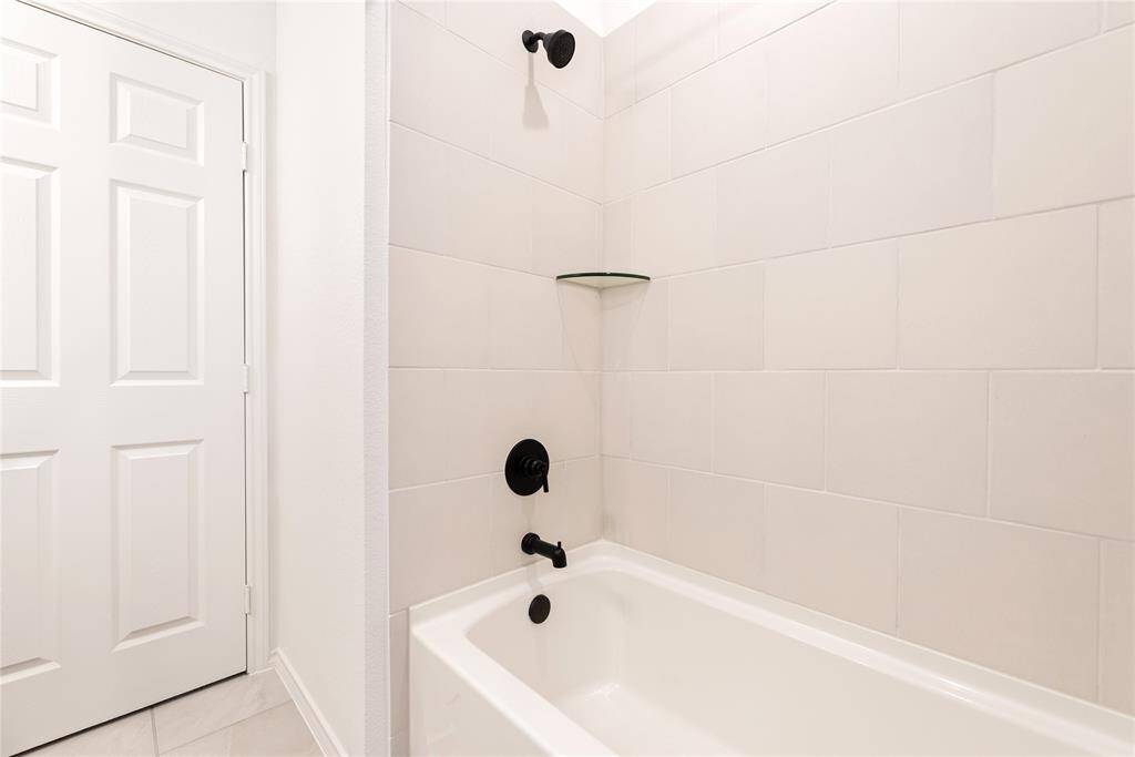 Secondary bathroom with a white tiled bathtub and shower area