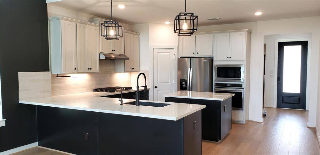 kitchen, from another angle, notice the deep & wide & deep kitchen sink with Gooseneck faucet. Notice the undermount lighting arrangements & the Island countertops, and ideal area for meal preparation!
