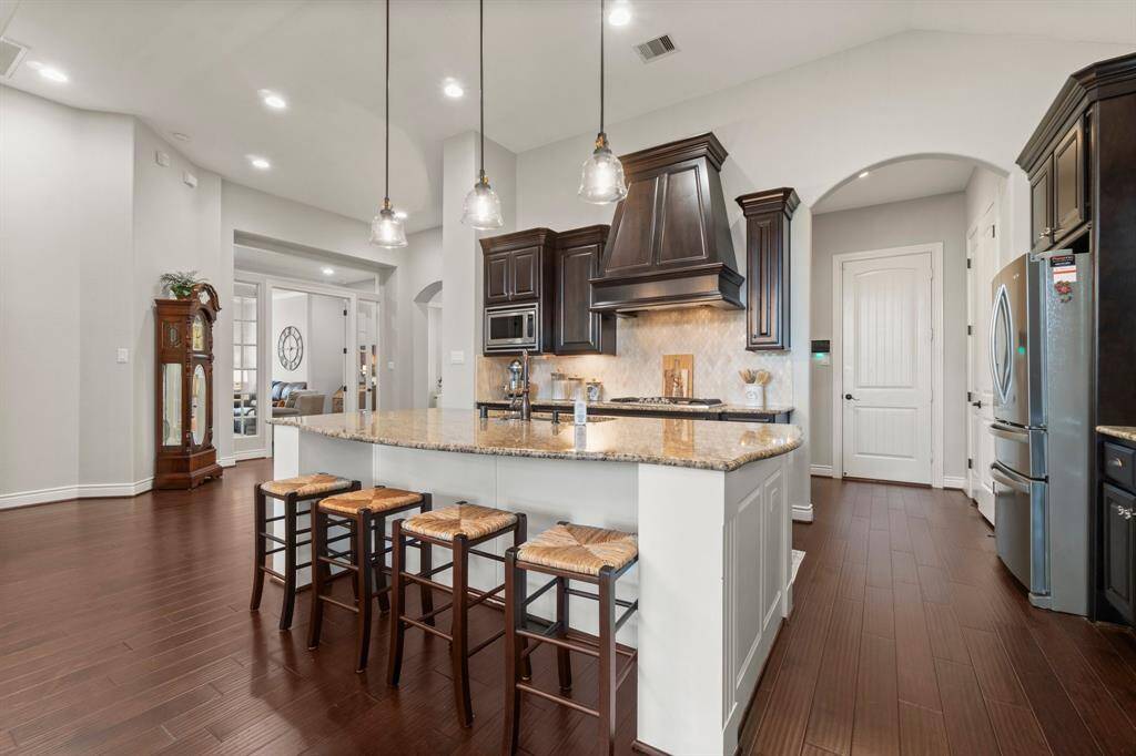 The kitchen boasts stainless steel appliances, a large island, and generous cabinetry.