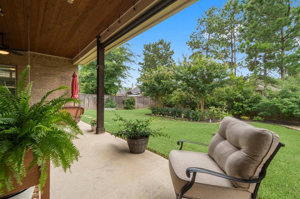Enjoy the covered patio with a stained tongue-and-groove ceiling, surrounded by lush landscaping and pavers.