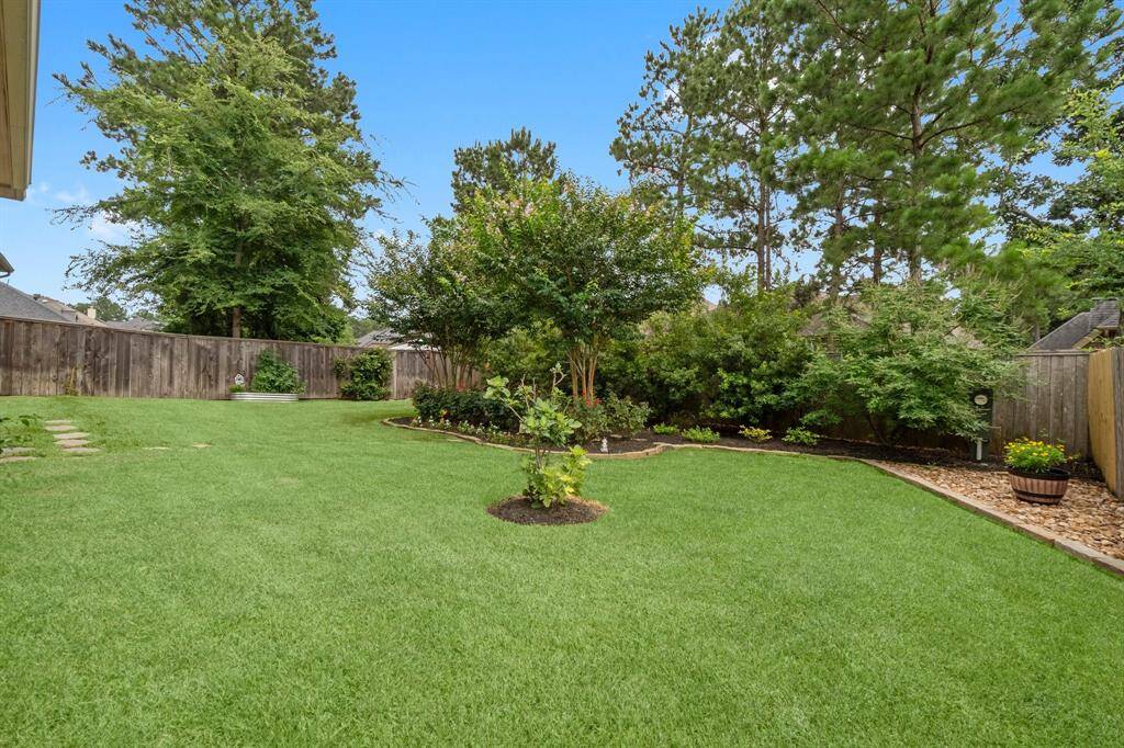 Enjoy the covered patio with a stained tongue-and-groove ceiling, surrounded by lush landscaping and pavers, with plenty of space for a future pool.